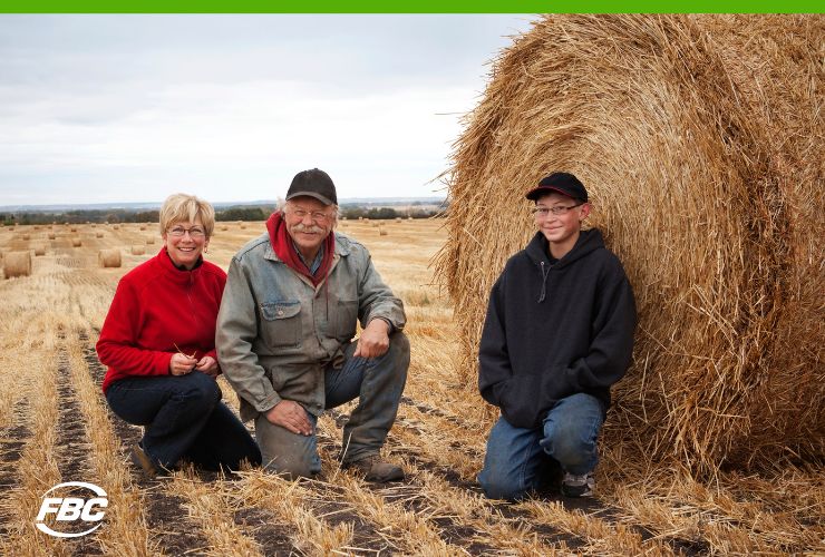 Farming Family sitting in field with bales