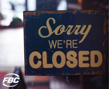 A "Sorry, we're closed" sign on a store window